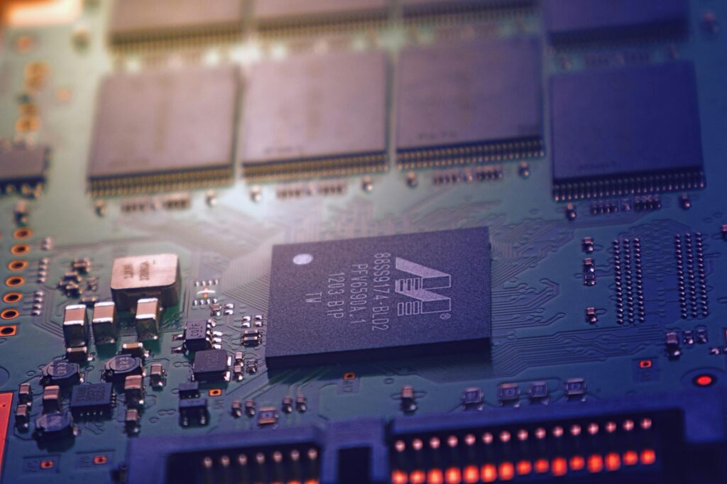 Home Detailed image of an electronic circuit board showing microchips and intricate wiring in a modern technological setting.